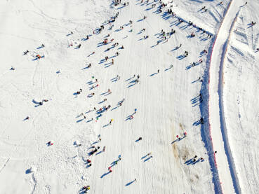 Ljudi se zabavljaju na planini, snimak dronom. Grupa turista na planini. Šetnja, skijanje i sankanje zimi. Djeca na snijegu. Zimski praznici. Sport i rekreacija.