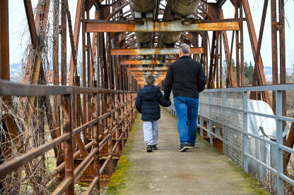 Djed i unuk šetaju na mostu. Koncept: generacija, nasljedstvo, ljubav, porodica.