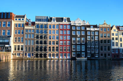 Amsterdam, Holandija: Poznate kuće u gradu Amsterdamu. Tipične holandske kuće sa šarenim fasadama. Kuće uz riječni kanal u centru grada. Historijske građevine.