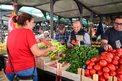 Ljudi kupuju svježe povrće na pijaci. Prodavačica prodaje svježe voće i povrće na lokalnoj pijaci.