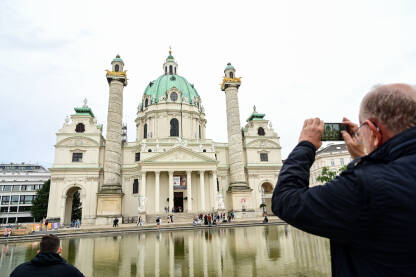 Beč, Austrija: Ljudi ispred crkve i fontane. Turisti fotografišu crkvu u gradu. Karlskirche ili Karlova crkva.