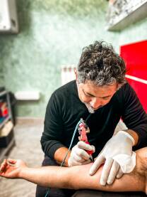 Tatto majstor tetovira ruku svog klijenta.