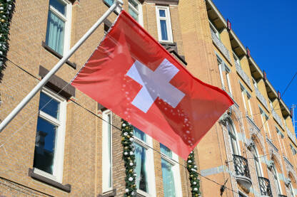 Zastava Švicarske na jarbolu u gradu. Nacionalna zastava Švajcarske.