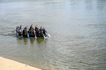 Ljudi treniraju u čamcu na rijeci. Grupa ljudi vesla. Sport i rekreacija.