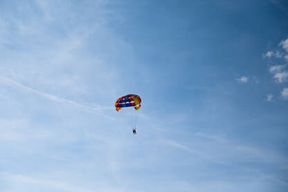 Padobran i čamac na moru tokom ljeta. Turist se zabavlja s padobranom na nebu. Ekstremni sport i avantura. Parasailing.