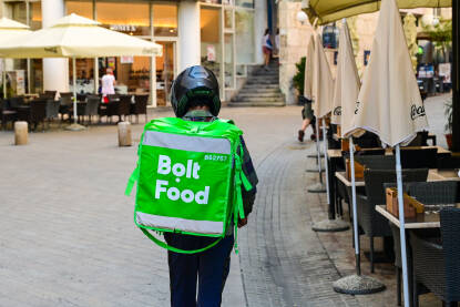 Bolt dostavljač hrane. Kurir za dostavu hrane na ulici. Čovjek s velikom zelenom Bolt torbom.