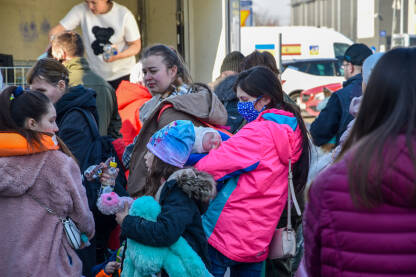 Djevojka drži bebu i čeka da uđe u autobus. Žene i djeca iz Ukrajine stigle u Poljsku.