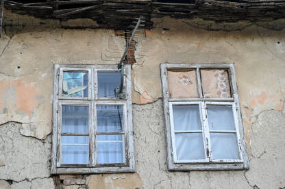 Stari prozori i fasada na ruševnoj kući. TV antena na zidu.