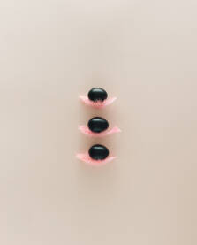 Uskrsna pozadina s tri crna jaja na roze perima.