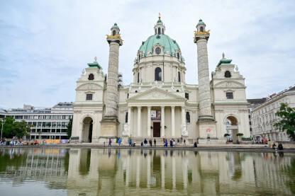 Beč, Austrija: Ljudi ispred crkve. Fontana. Turisti istražuju grad. Karlskirche ili Rektoratska crkva sv. Karla Boromejskog.