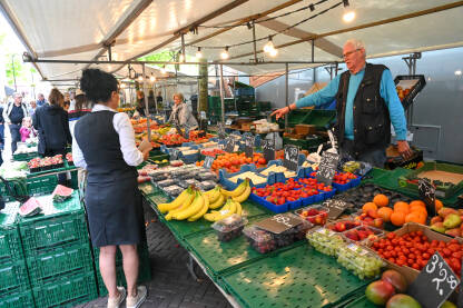 Ljudi kupuju voće i povrće na pijaci. Trgovci na tržnici.