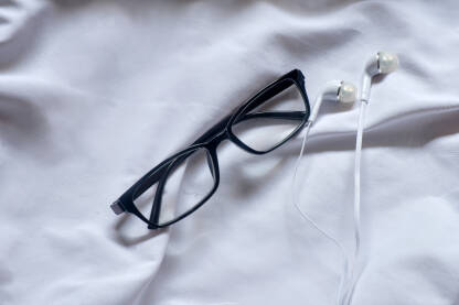 Naočale sa dioptrijom i slušalice za uši na bijeloj pozadini