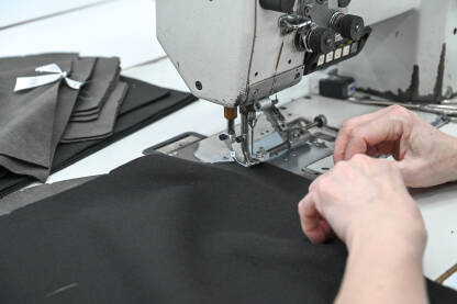 Žena šije tekstil šivaćom mašinom. Radnica radi u fabrici.