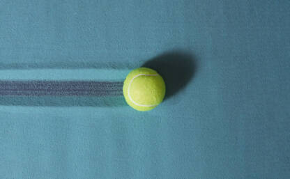 Žuta tenis loptica u plavom pijesku.