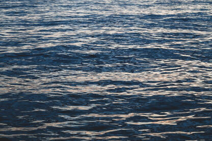 Refleksija svjetlosti na morskoj površini. Morski valovi pri zalasku sunca. Odraz sunčeve svjetlosti na površini vode. Duboko plavo more.