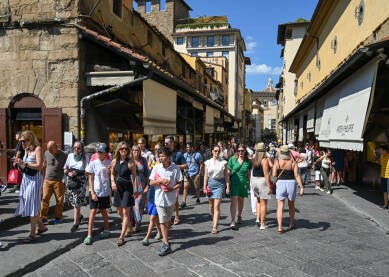 Firenca, Italija: grupa turista na mostu Vecchio. Ljudi šetaju gradom. Historijske zgrade u centru grada.