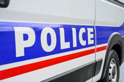 Policijski automobil na ulici. Bočni pogled na policijski automobil sa natpisom "Policija". Policijsko patrolno vozilo parkirano na ulici.