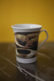 Bela soljica za caj ili kafu sa detaljima kafe na sebi , zuta i siva pozadina