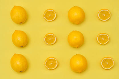 Pogled odozgo na limun s polovicama i cijelim zrelim limunima na žutoj pozadini