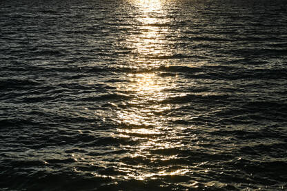 More tokom zalaska sunca. Tamnoplava voda. Okeanski valovi i refleksija sunca.