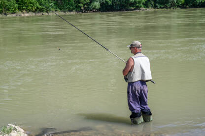 Ribar lovi ribu u rijeci. Ribolovac sa ribarskim štapom u vodi.