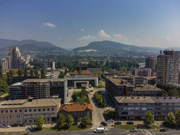 Grad Zenica, u sredini zgrada Bosanskog narodnog pozorišta Zenica, lijevo u pozadini Lamela, desno naprijed zgrada Gradske uprave i MUP-a ZDK, a u pozadini desno zgrada RMK Prometa, sjedište Vlade ZDK
