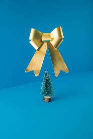 Božićno, novogodišnje drvce s velikom zlatnom mašnom u zraku. Blagdanska čestitka.