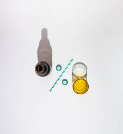 Boca za pivo i staklena čaša s papirnom slamkom za piće i dva čepa u obliku znaka za postotak.