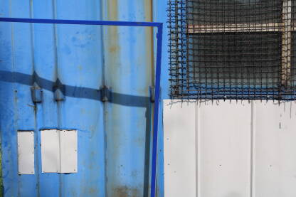 Stranice plavog limenog kontenera sa geomerijom inervencija: prozori, zaštitne mreže, dodtne pozicije, okviri...