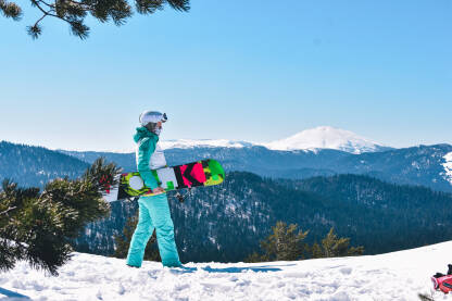 Djevojka drži bord u ruci na vrhu planine. Skijalište na Kupresu.