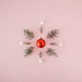Crvena božična kuglica, ukras s grančicama bora i bijelim pamučnim kuglicama. Božićna, novogodišnja čestitka.