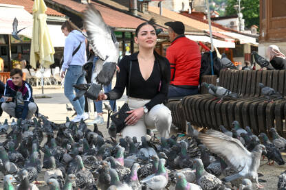 Djevojka sa golubovima. Turisti na Baščaršiji u Sarajevu.
