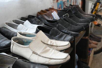 Mnogo cipela poredanih na polici. Polovne cipele u hodniku kuće. Kožna obuća. Stare trošne cipele.