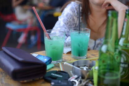 U kafiću na stolu posluženi plavi kokteli sa slamčicama i pivo. Druženje uz alkohol i cigarete.