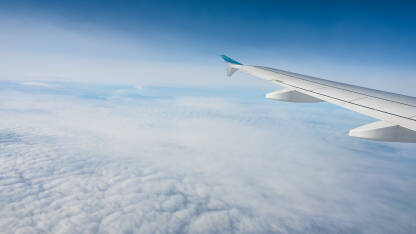 Krilo aviona, pogled kroz prozor. Let mlaznim avionom iznad bijelih oblaka.