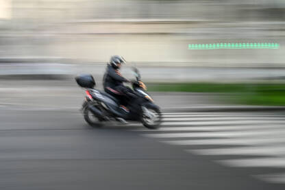 Zamoćena fotografija motocikla koji se brzo kreće ulicom. Vozač brzo vozi  motocikl u gradu. Motociklista vozi velikom brzinom.
