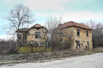 Oštećene i ruševne kuće u selu. Stare napuštene kuće u unutrašnjosti zemlje. Rustikalni dom. Stara kuća napravljena od gline sa drvenim prozorima. Iseljavanje sa sela.