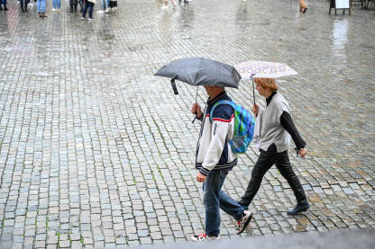Brisel, Belgija: Ljudi na glavnom trgu u centru grada s kišobranom u ruci dok pada kiša. Turisti hodaju.