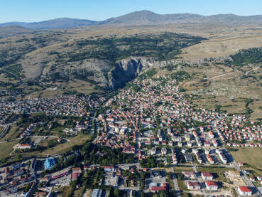 Grad Livno, BiH, panorama grada, brdo Bašajkovac i planina Cincar. Panoramski pogled na zgrade, kuće i ulice, snimak dronom.