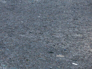 Razni oblici komunalnog otpada nagomilani u rijeci Drini, vidljivi na površini i uz obalu.