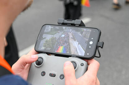 Muškarac upravlja dronom. Mladi muškarac drži kontrolor drona i snima događaj u gradu.