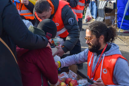 Volonter Crvenog krsta dijeli hranu izbjeglicama iz Ukrajine, na prelazu Medyka u Poljskoj.