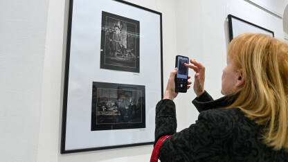 Posjetioci posmatraju fotografije u galeriji. Ljudi na izložbi. Posjetioci posmatraju i fotografišu fotografije u galeriji.