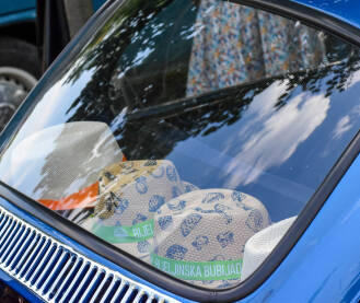 Izložba starih automobila na bijeljinskoj bubijadi. Šeširi koji se vide kroz prozor oldtajmera. Na šeširima piše bijeljinska bubijada.