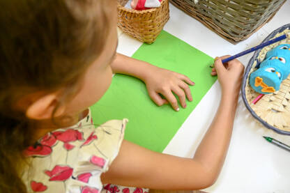 Djevojčica crta na bloku. Djevojčica crta šarenim olovkama. Obrazovanje djece.