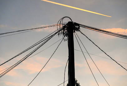 Mnoštvo električnih kablova na banderi tokom zalaska sunca sa avionom u pozadini. Električna energija. Prijenos električne energije.