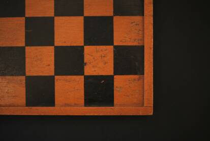 Jedan deo sahovske table u kadru sa kockicama dveju razlicitih boja, tabla od drveta