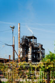 HI „Destilacija” Teslić, dimnjak i dio pogona fabrike okružena drvećem i ogradom.