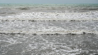 Mutna morska voda nakon kiše. Olujno nevrijeme na obali. Valovi mora s pješčanom sivom i smeđom bojom.