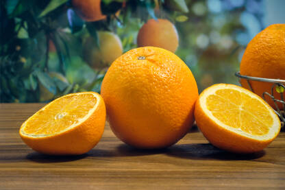 Narandže i kriške na stolu u pozadini plodovi na granama